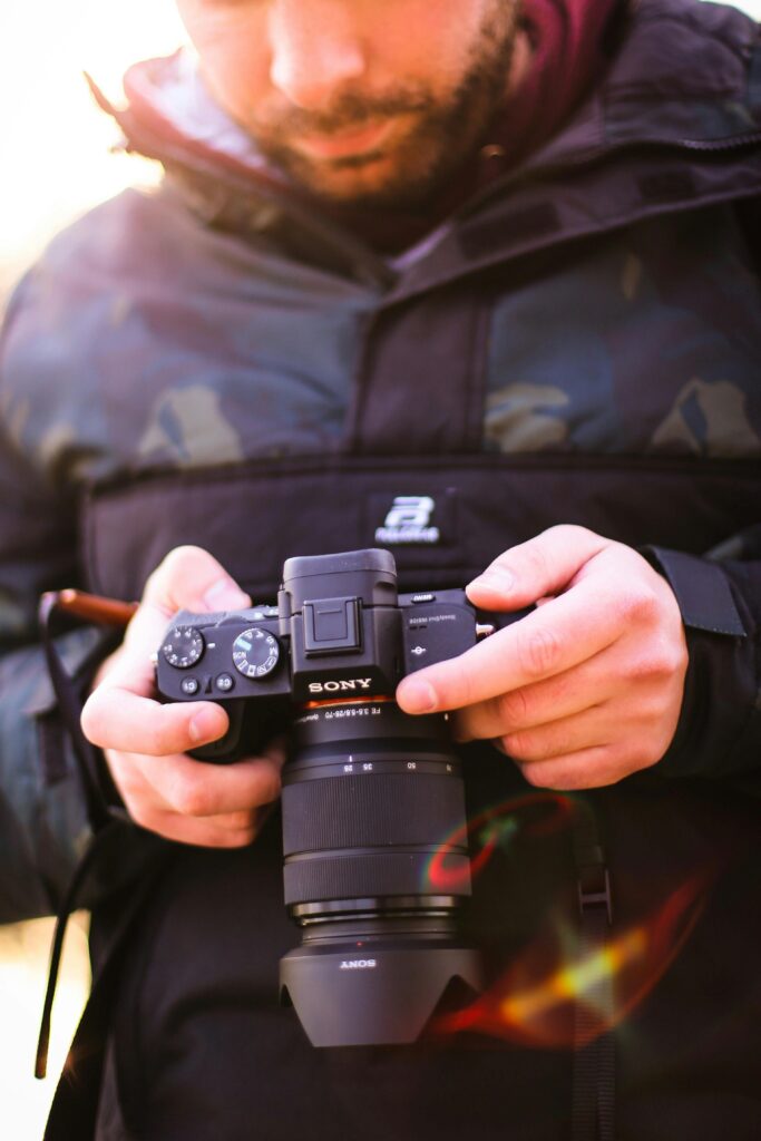 Man adjusting settings on a digital camera outdoors, highlighting photography concept.